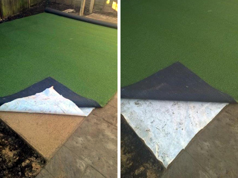 These two photos show a corner of the lawn yet to be laid, and you can see the compacted sand underneath (mentioned in last month’s blog) and then the crucial white membrane (also described in last month’s blog, it acts as a barrier as well as allowing drainage to occur) which is the sandwich between the ground and the final layer of artificial grass. Seen like this the process resembles that of laying an outside carpet and the neat timber edging holds the lawn securely in place.