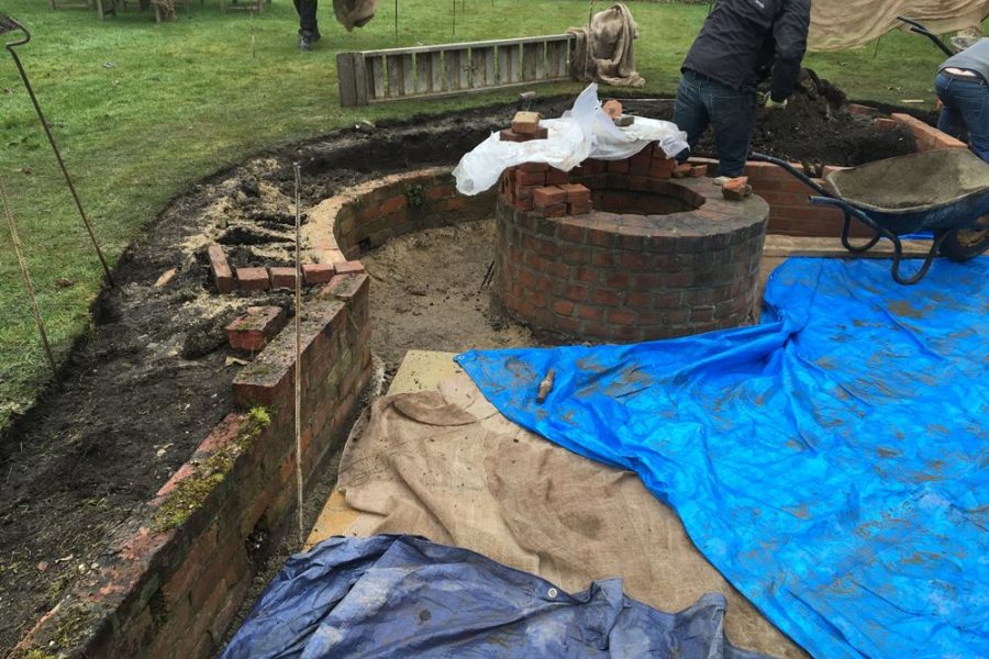 Before photo showing the existing brick wall and the team levelling the soil ready for the brick pavers to be laid on top.