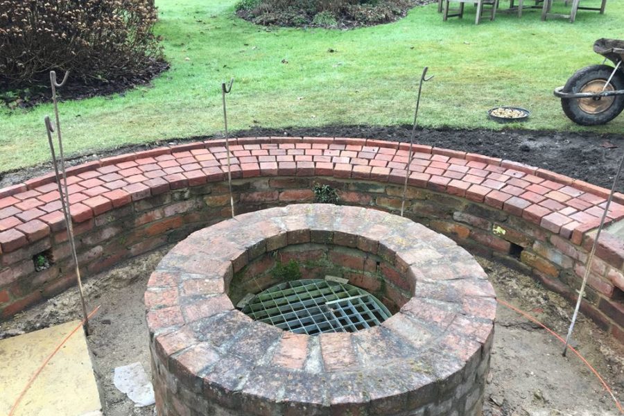 The new brick seat takes shape; steel markers are used to produce an accurate circle of bricks surrounding the well.